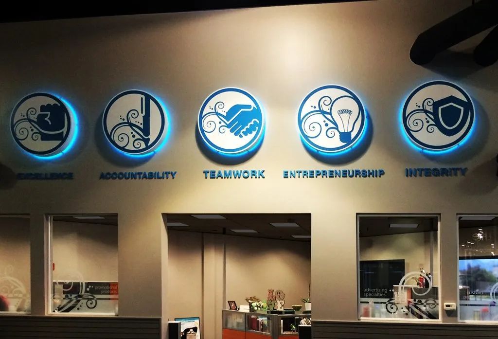 Wall with five blue circular value icons above a reception counter in an office lobby