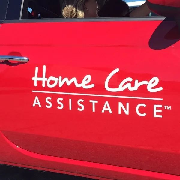 Red car door with white “Home Care Assistance” logo and text