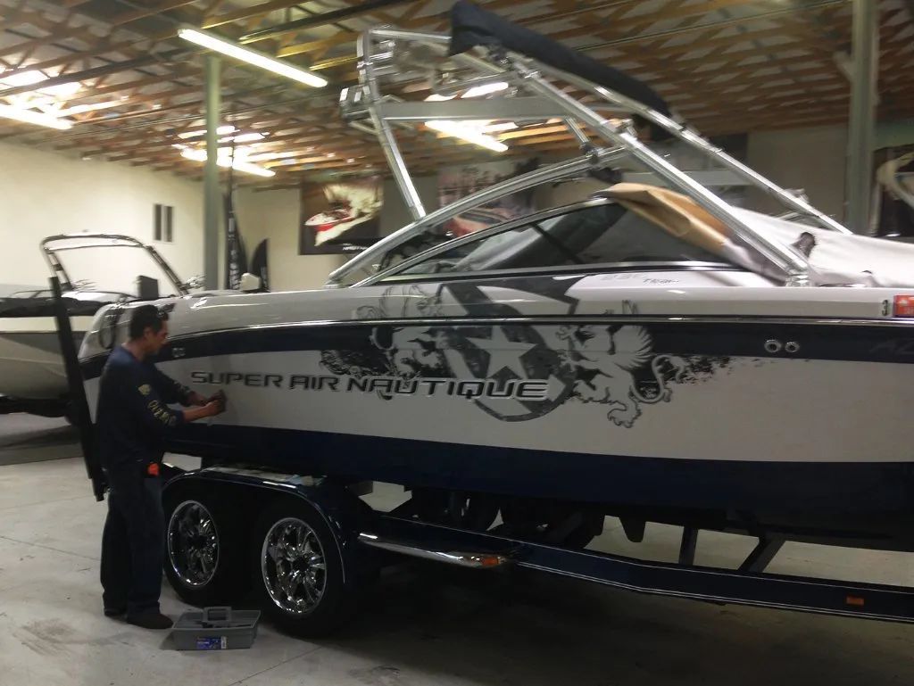 Person beside a black-and-white speedboat on a trailer inside a garage