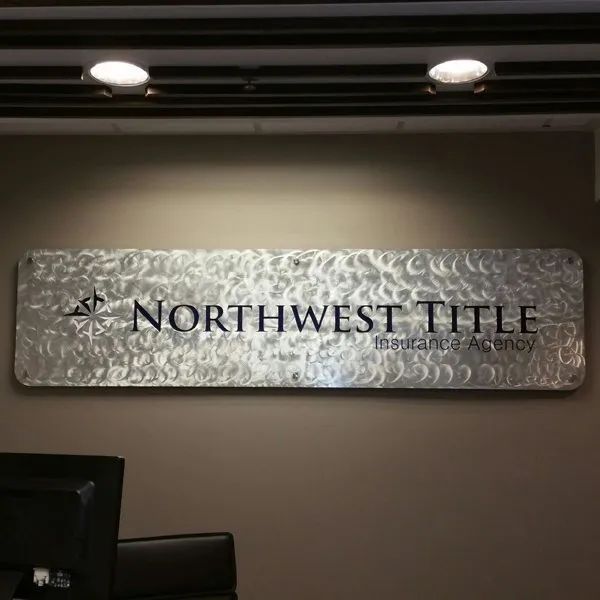 Northwest Title wall sign on a brown office wall under ceiling lights