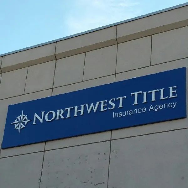 Blue Northwest Title Insurance Agency sign on a beige building exterior