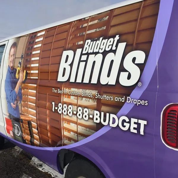 Budget Blinds van with purple wrap and large window-blind advertisement on the side