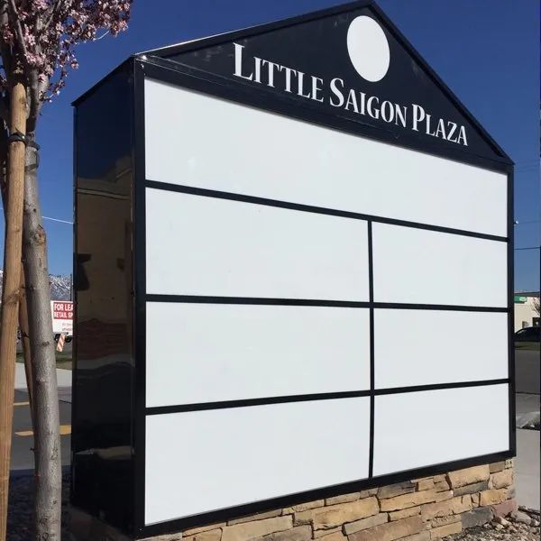 Little Saigon Plaza roadside sign with blank white panels and black trim under a blue sky