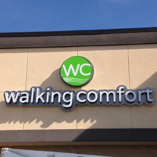 Walking Comfort storefront sign with green WC logo on a beige building facade