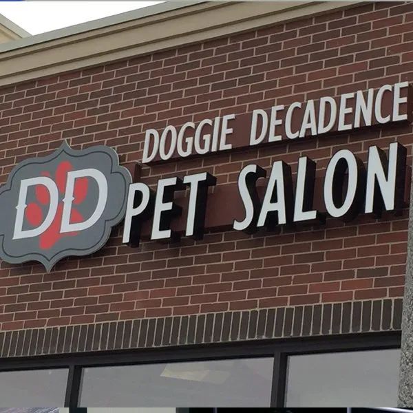 Doggie Decadence Pet Salon sign on a brick storefront with white and red lettering