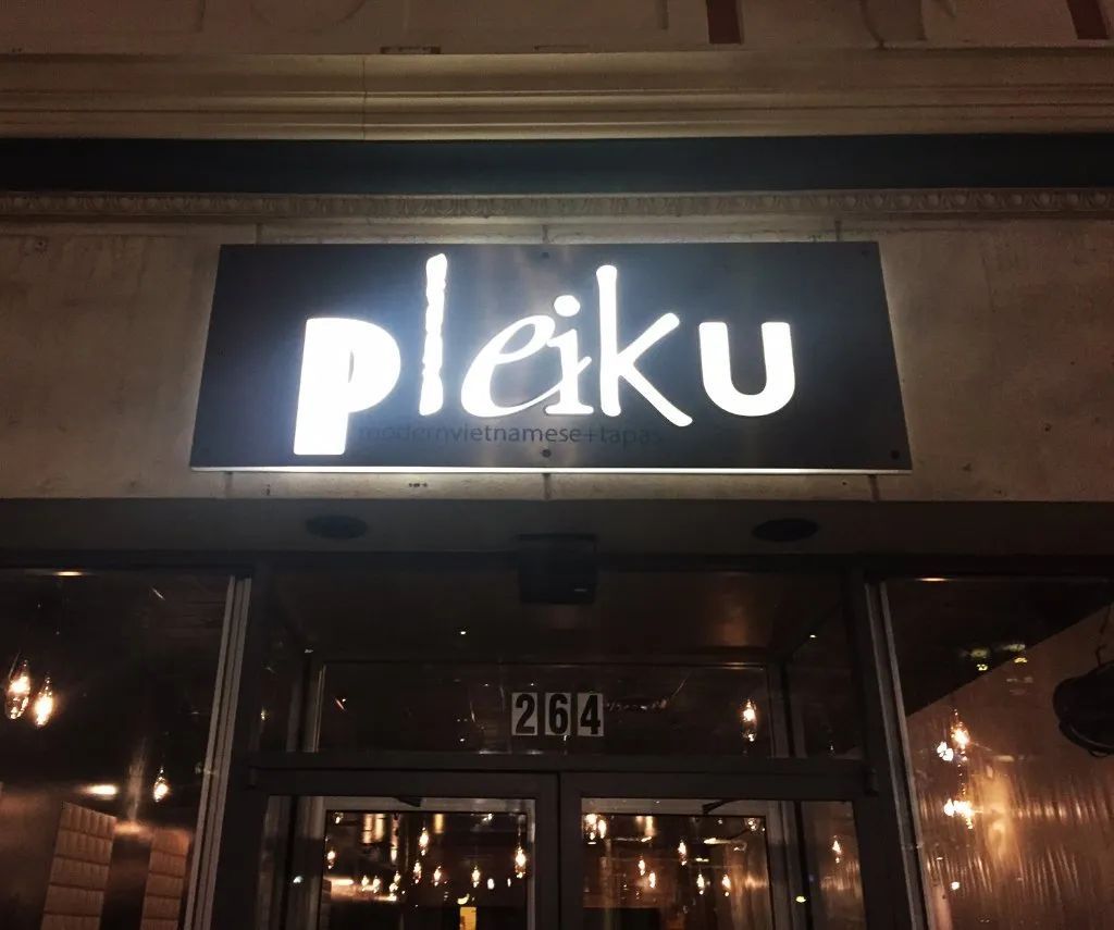 Bright “Pleik” sign above a warmly lit restaurant entrance at night