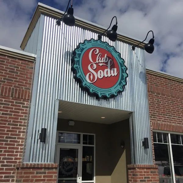 Club Soda sign above a brick-and-corrugated metal storefront entrance