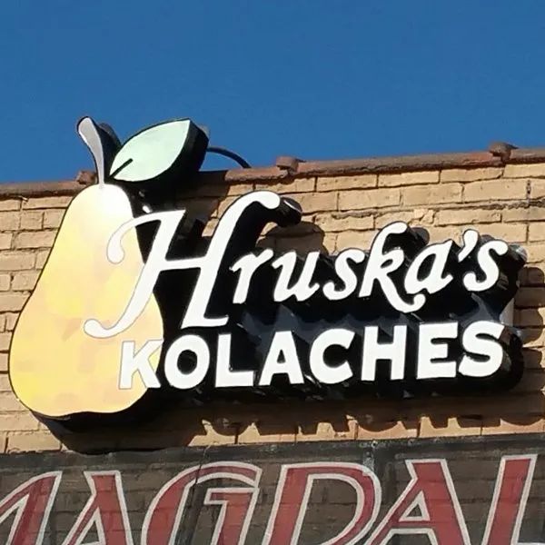 Hruska’s Kolaches sign with a pear logo on a brick building under a blue sky