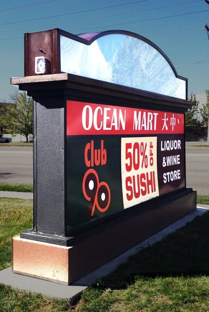 Ocean Mart sign with red “50% SUSHI” and “Liquor Wine Smoke Store” text outdoors.