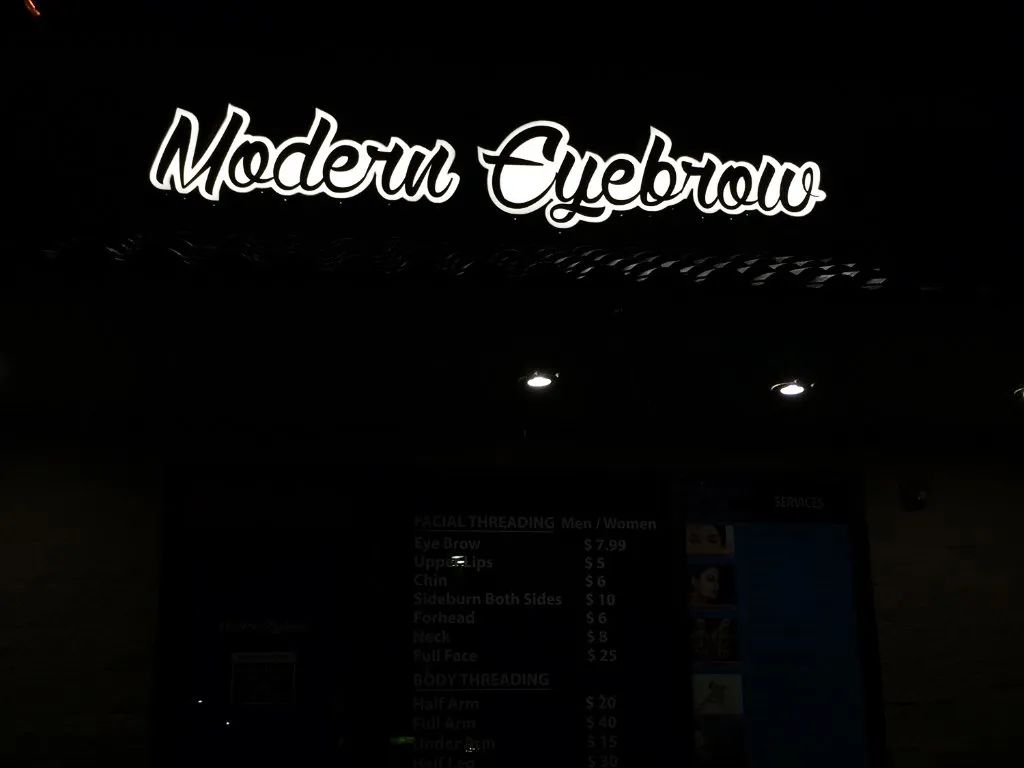 Dark storefront at night with a glowing “Modern Cypress” sign above the entrance.