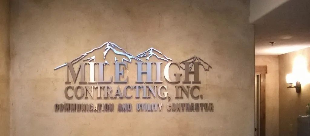 Wall sign reading “Mitch Contracting, Inc.” in metallic lettering on a beige lobby wall.