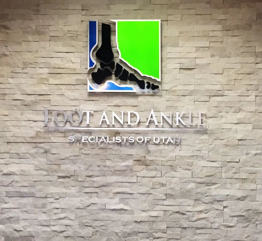 Podiatry clinic sign on stone wall with foot logo and text “FOOT AND ANKLE SPECIALISTS OF UTAH”