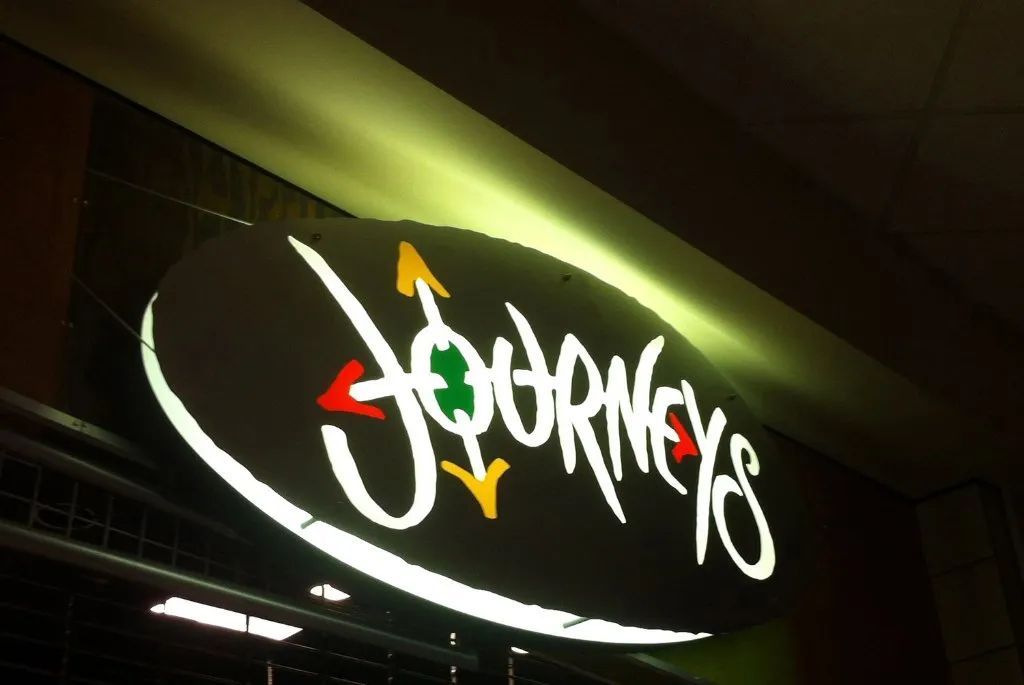 Stylized white “Journeys” store sign on a dark background with red, green, and yellow accents
