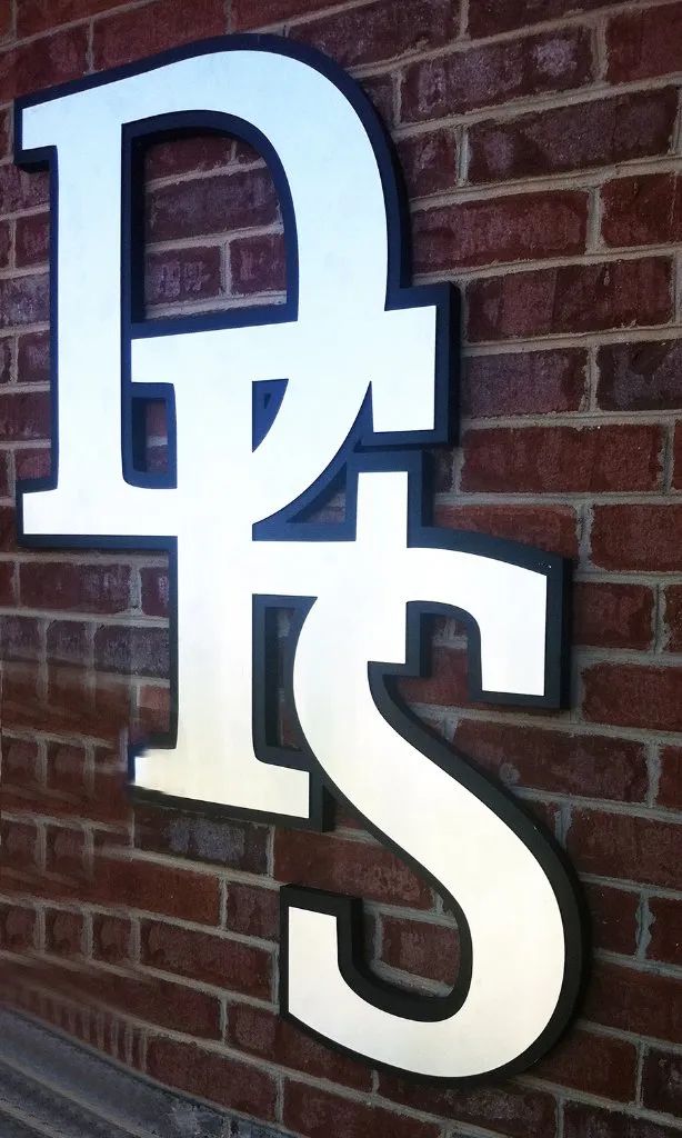 White “DHS” letters mounted on a brick wall