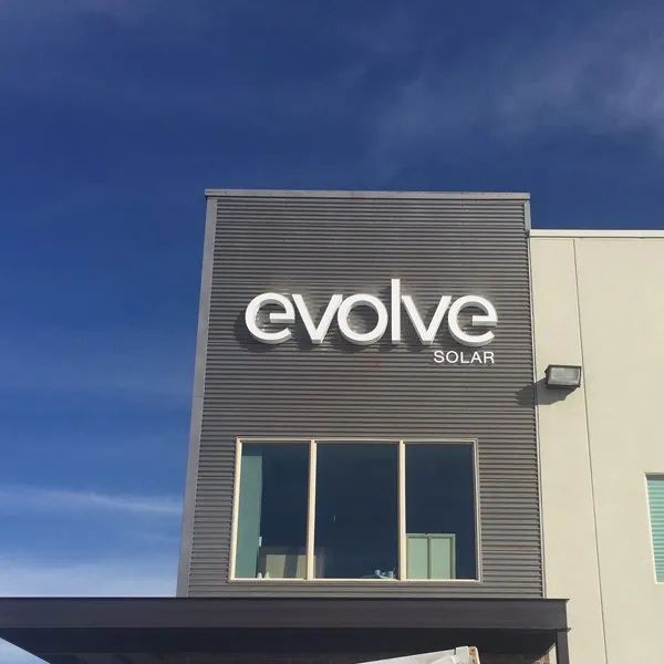 Evolve Solar sign on a gray building under a clear blue sky