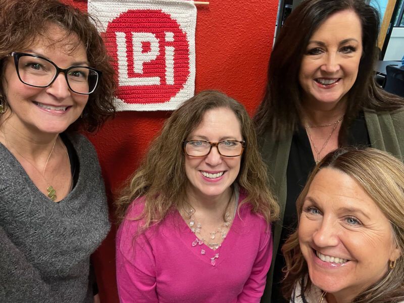 A group of women are posing for a picture in front of a red wall.