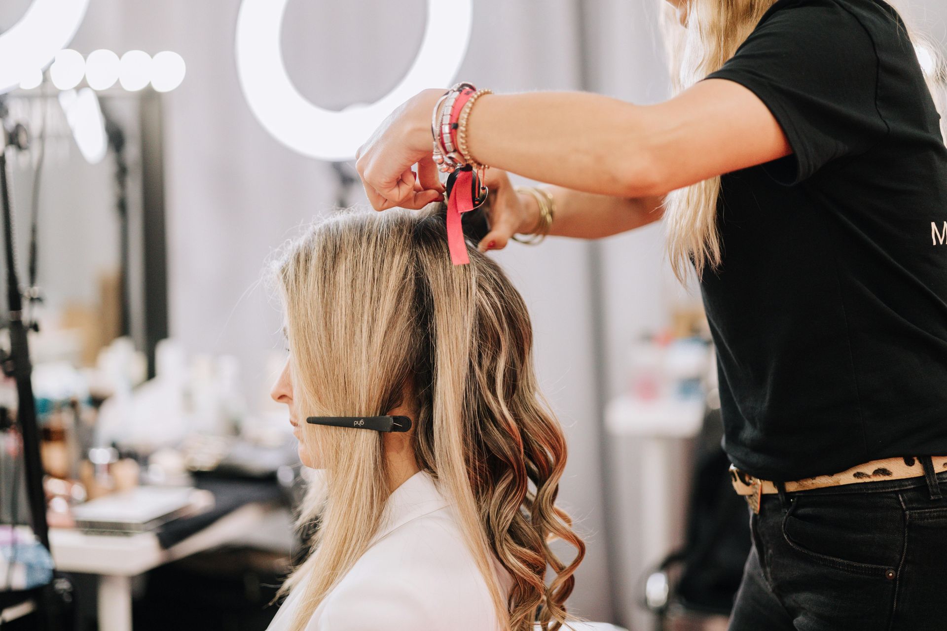 A hairstylist textures a client's hair with a crimping iron in a professional studio setting.