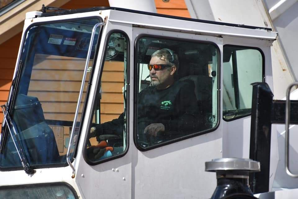 A man wearing sunglasses is driving a white truck