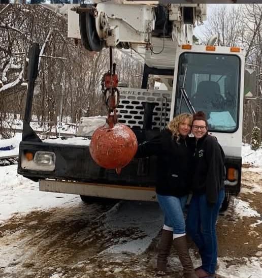 Two women standing in front of a crane in the snow