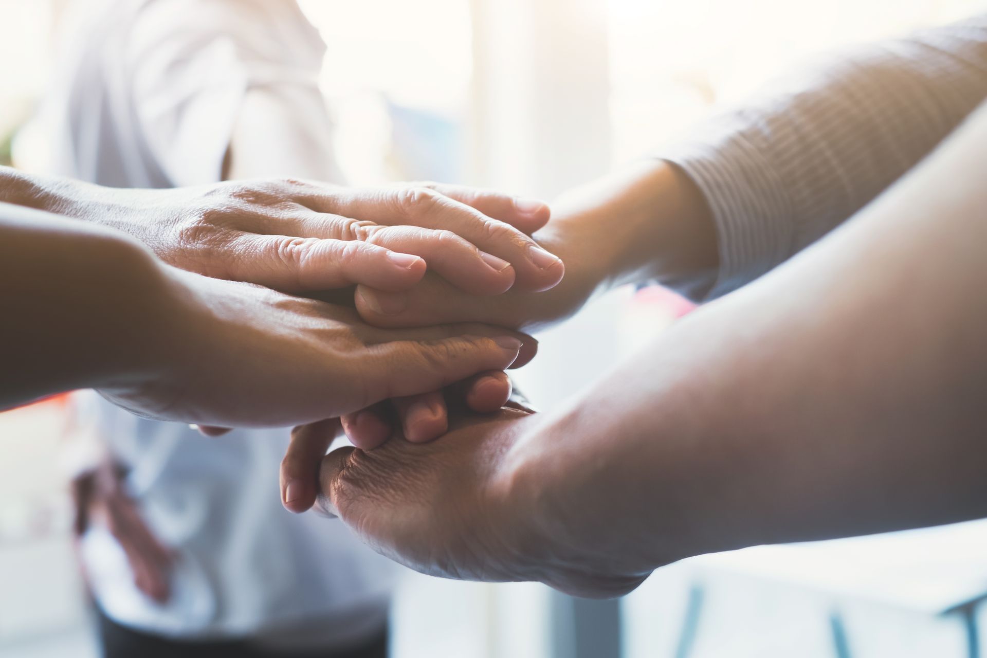 a group of people are putting their hands together .