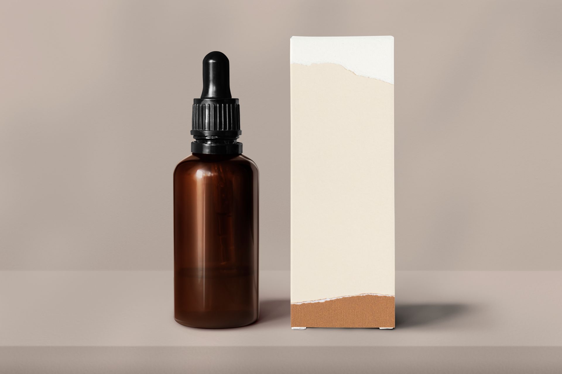 a brown bottle with a dropper and a box on a table .