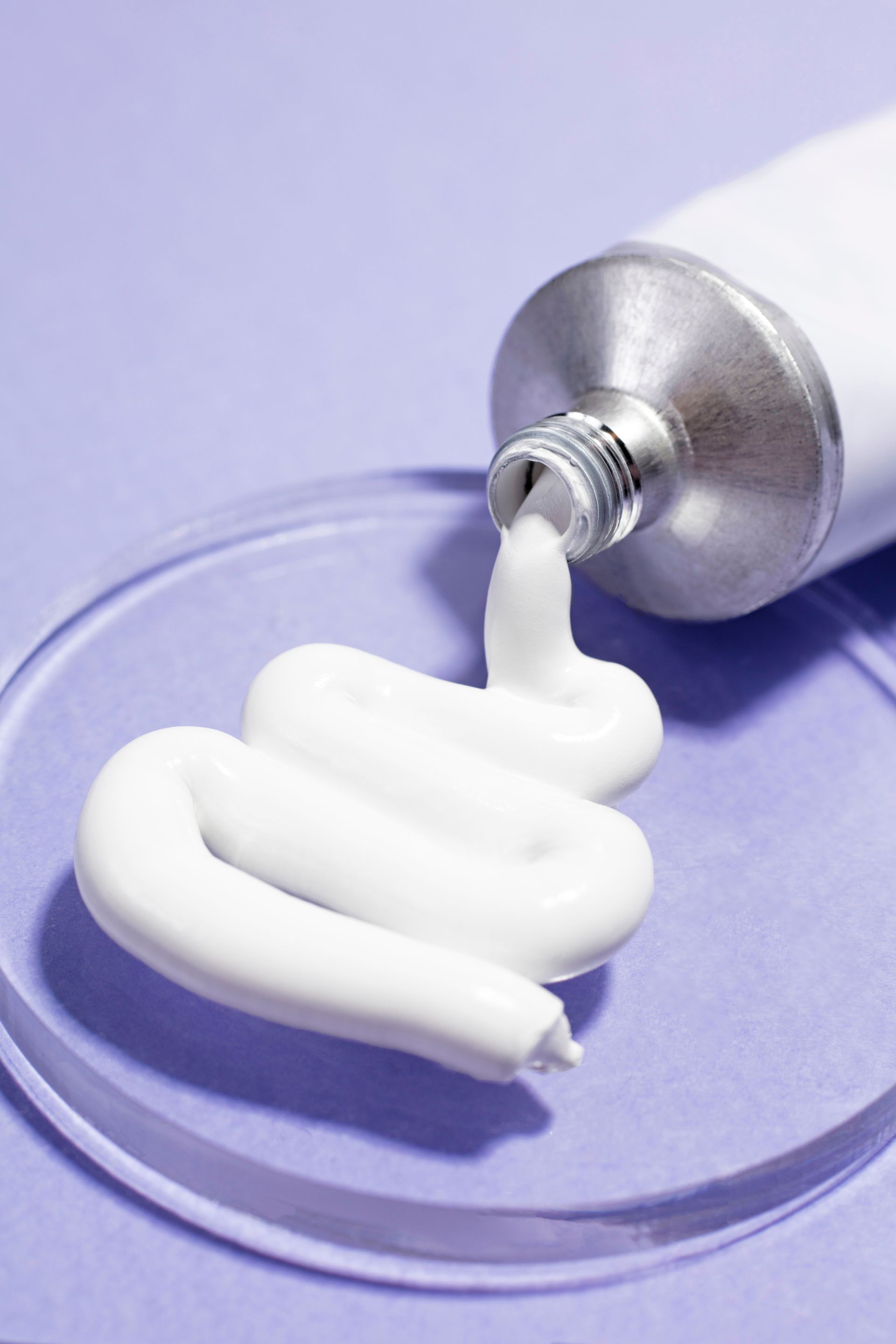 a tube of toothpaste is being poured onto a glass plate .