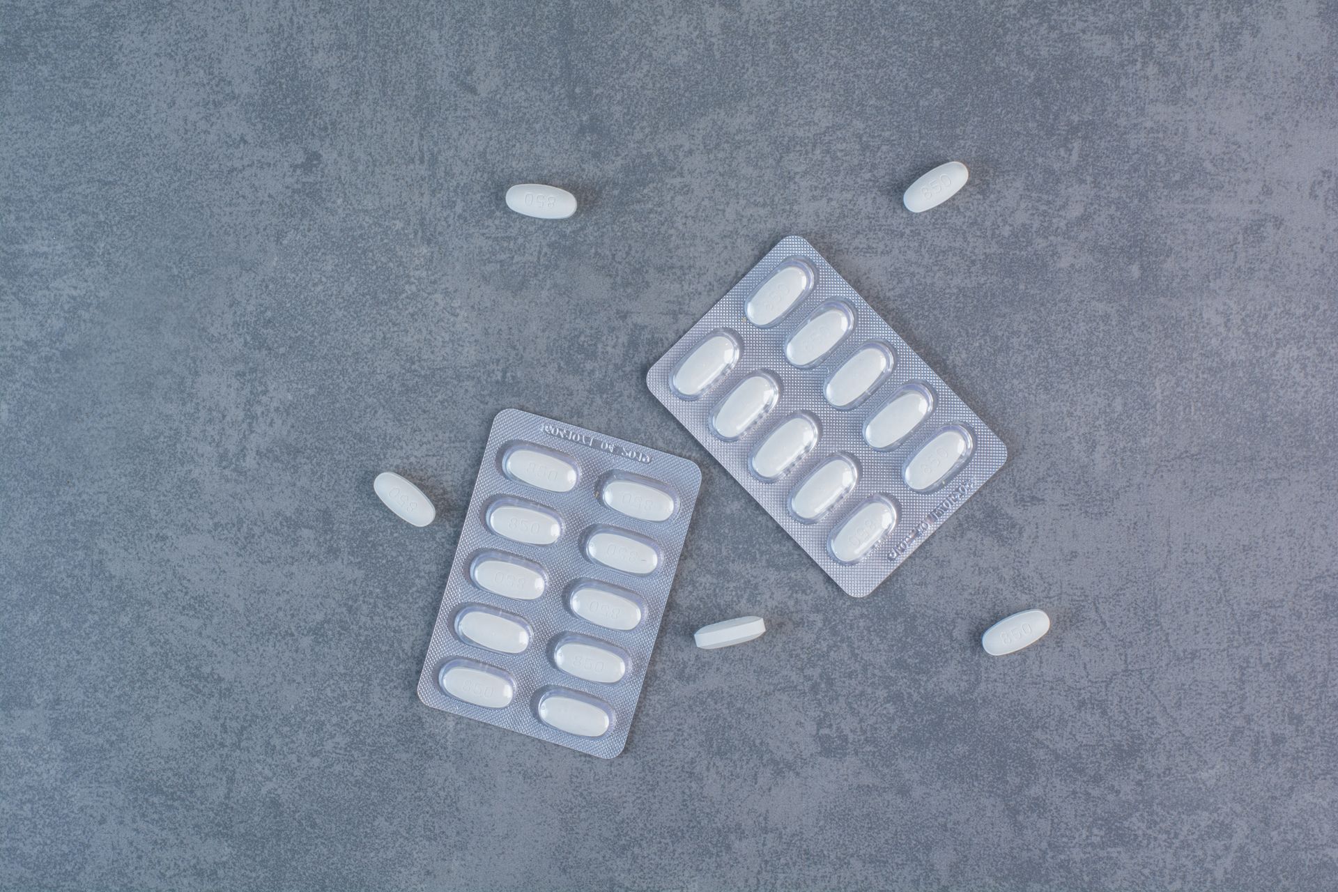 two blister packs of pills on a gray surface .