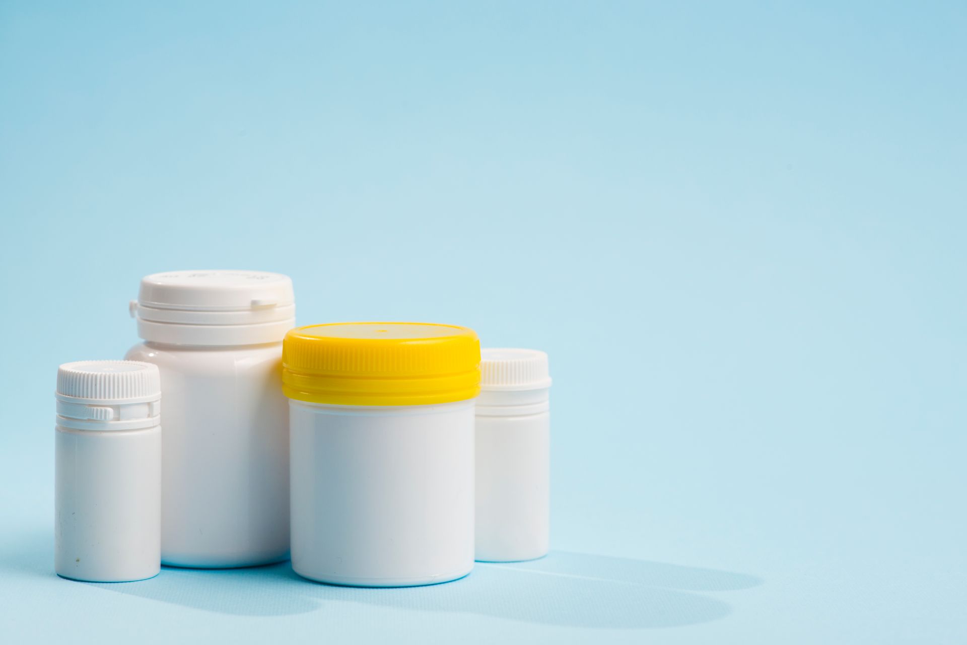 a group of white plastic bottles with yellow lids on a blue background .