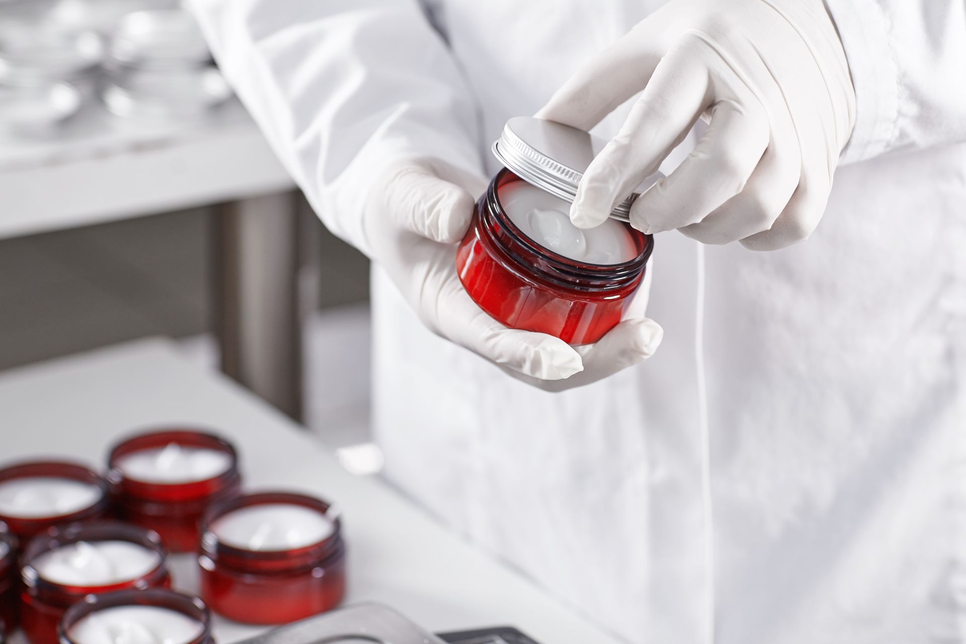 a scientist is holding a jar of cream in his hands .
