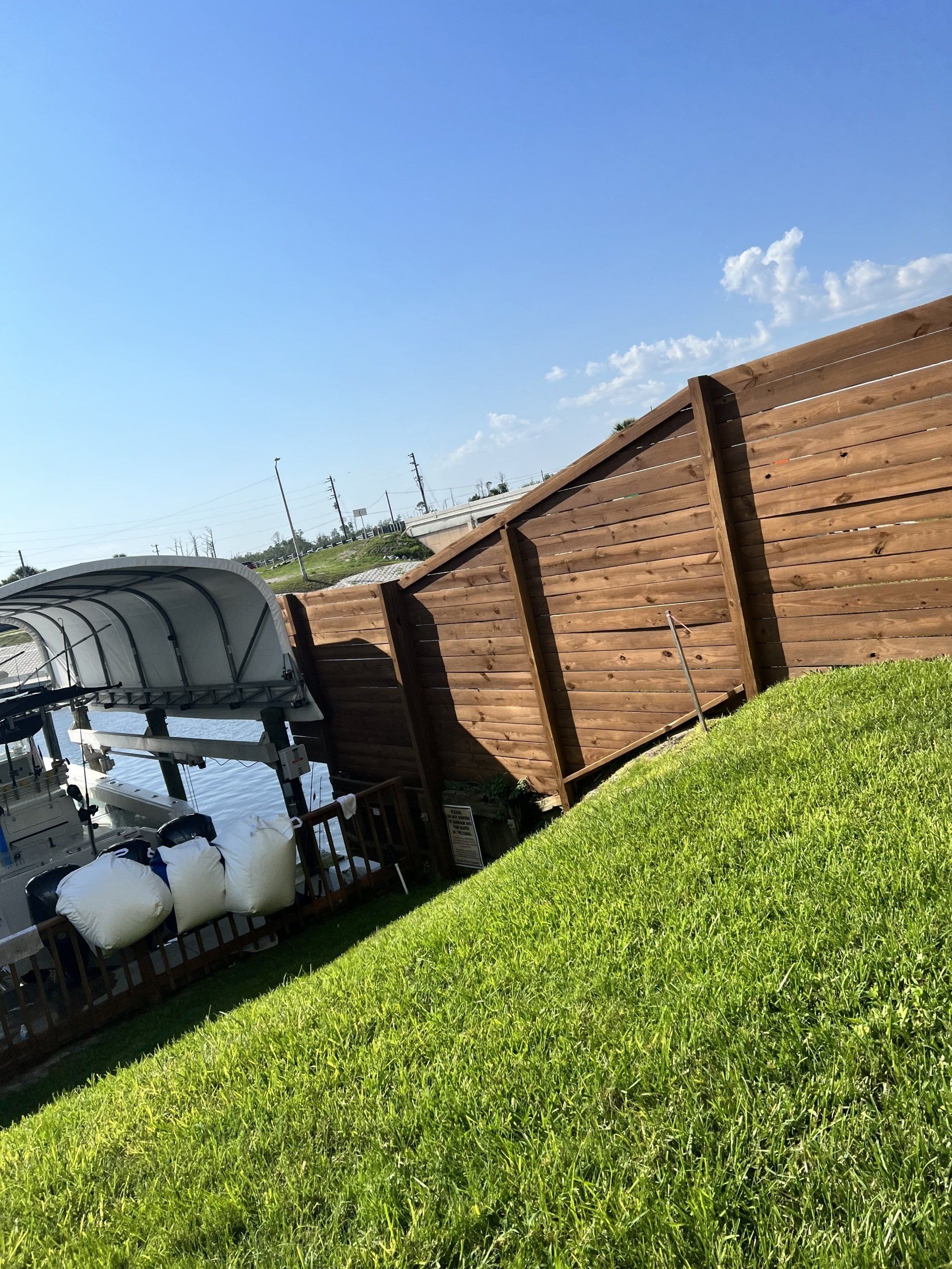 Green grass hillside, brown wooden fence, and blue sky.