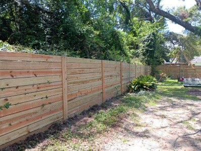 Wooden fence along a grassy area, with trees in the background.