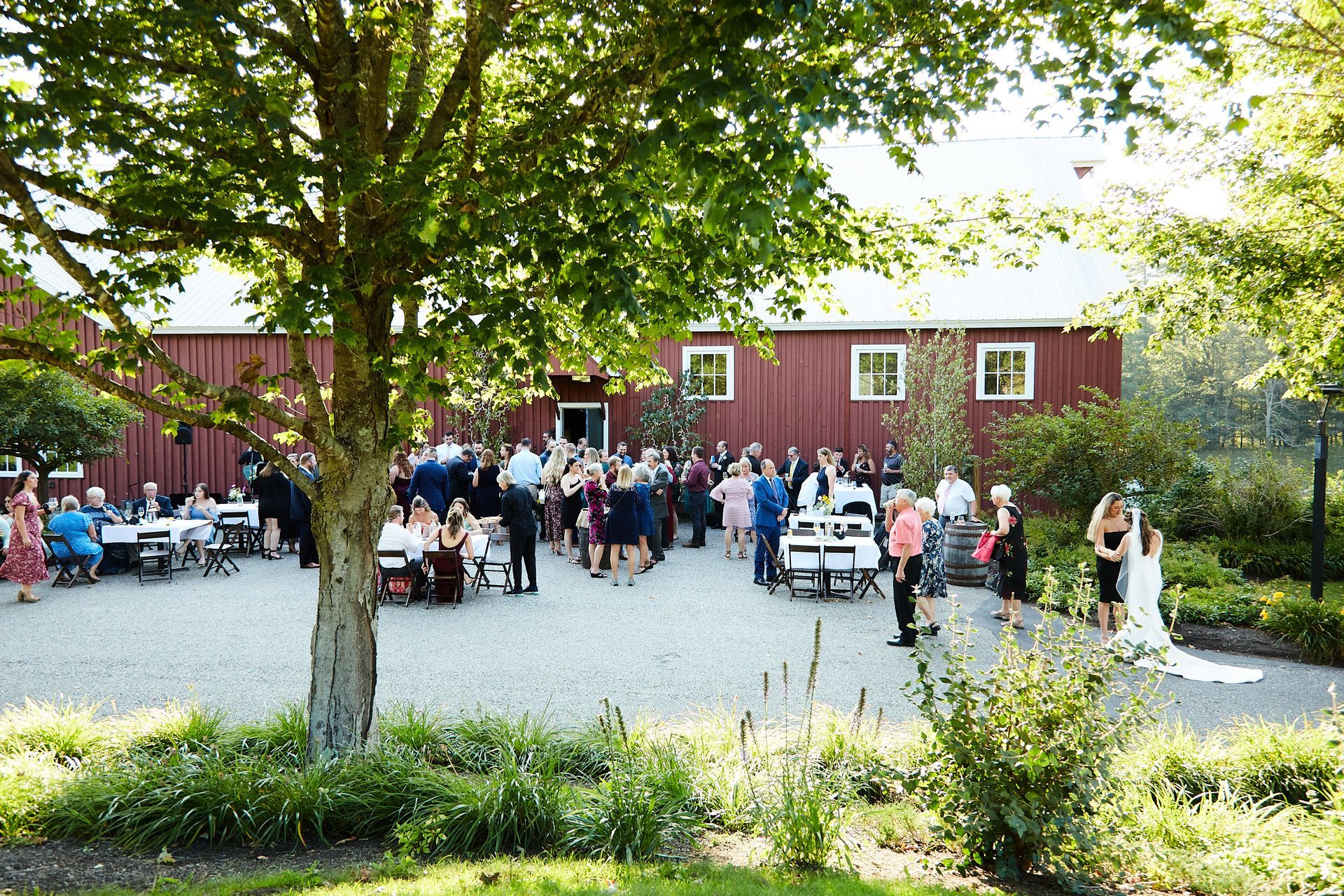 A large group of people are gathered in front of a red barn.