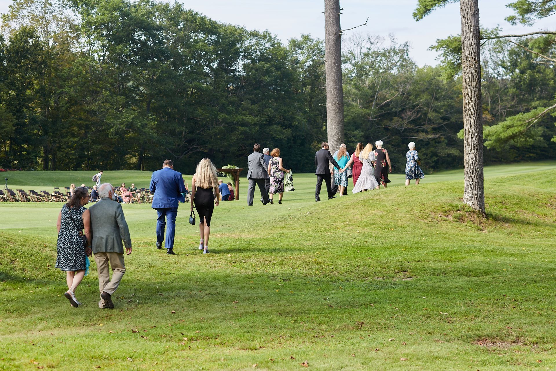 A group of people are walking through a grassy field.
