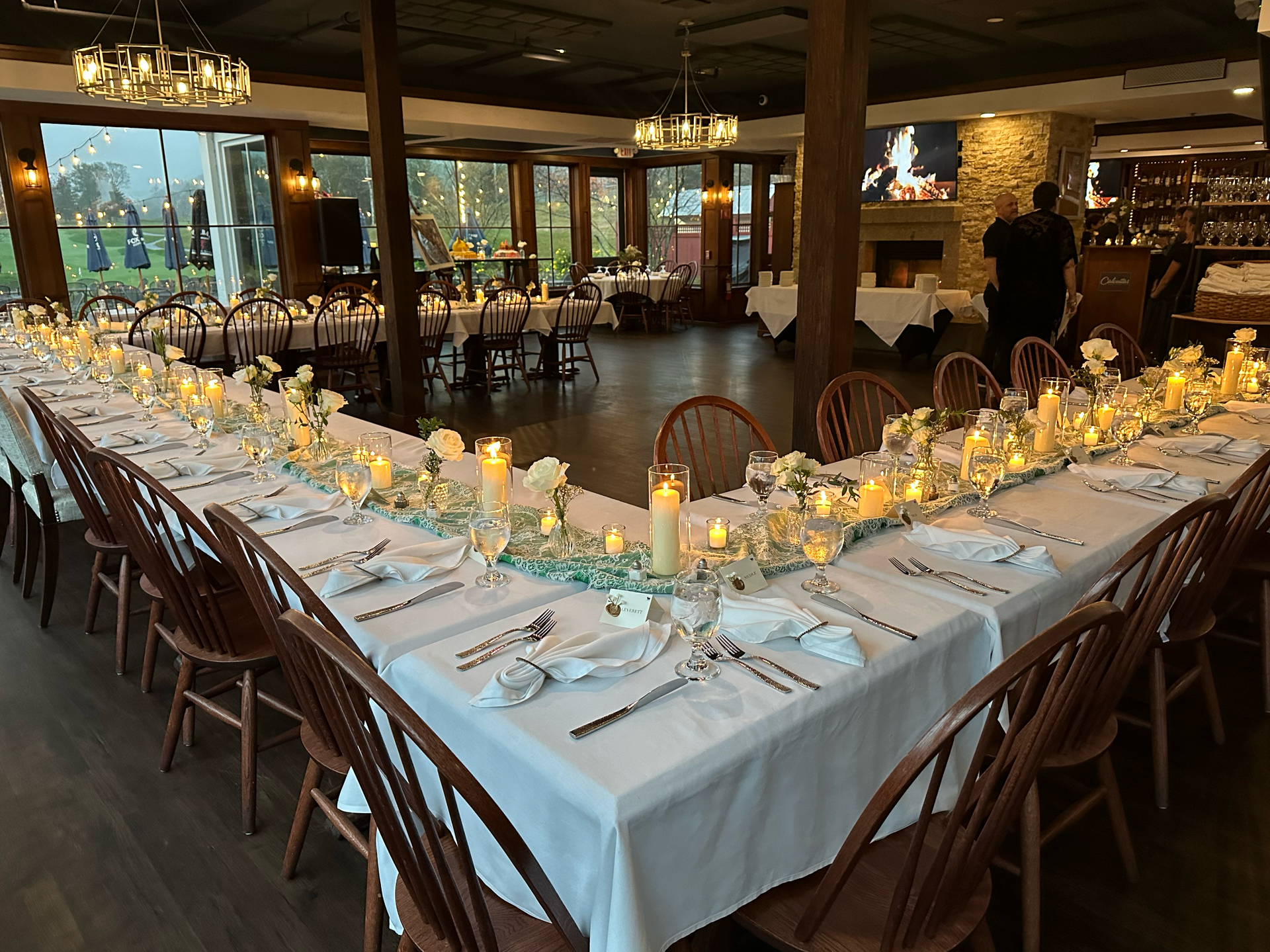 Formal dining tables with candles and flowers set in a restaurant.