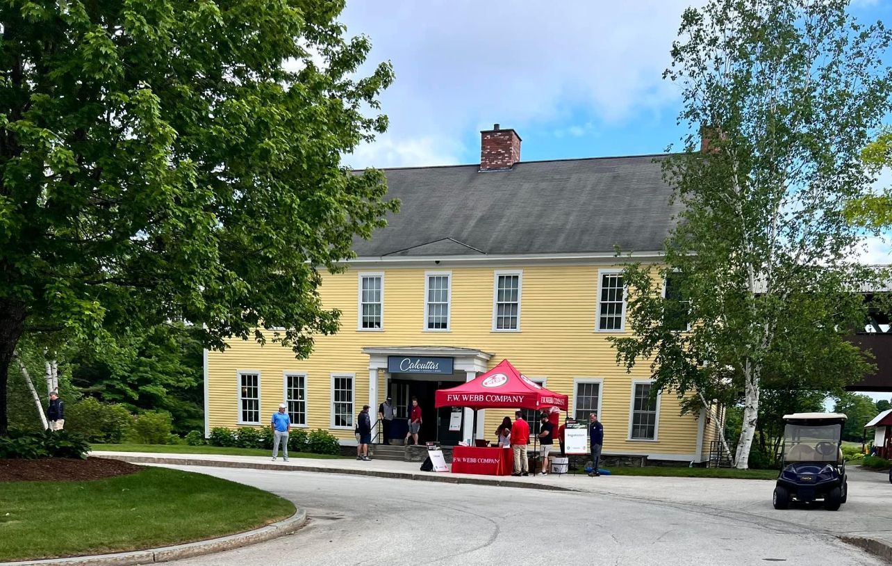 Yellow building with people, red tent, and golf cart outside.