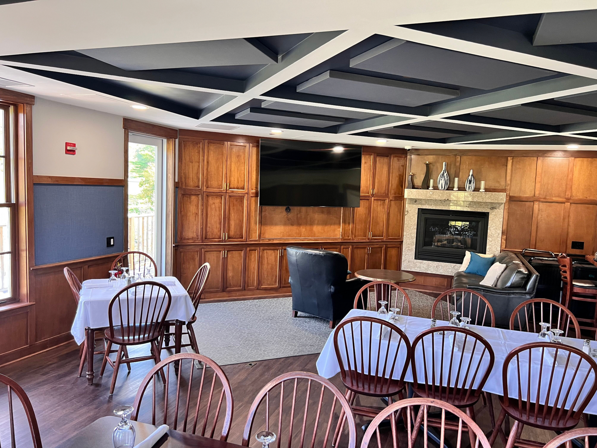 A large dining room with tables and chairs and a fireplace.