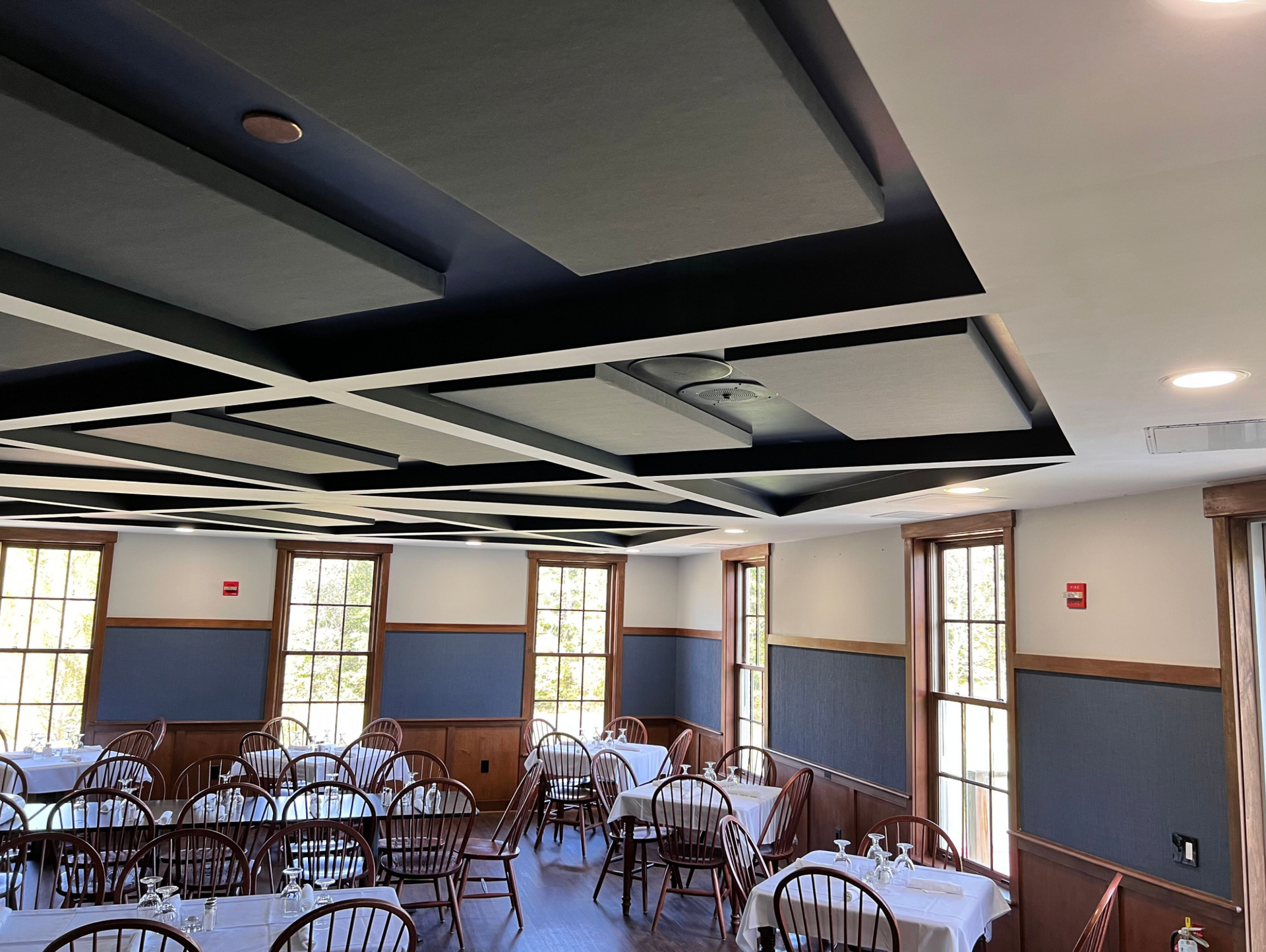A large dining room with tables and chairs and a coffered ceiling.