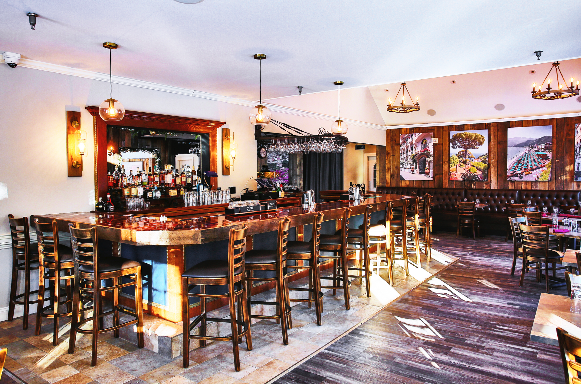Interior of a restaurant with a long wooden bar and bar stools. Tables and chairs in the dining area.