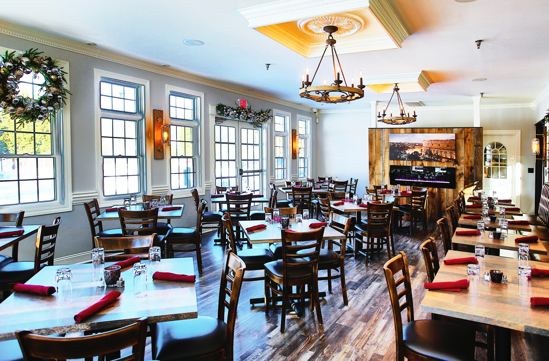 Restaurant interior with tables set for dining, windows, and decorative lights.