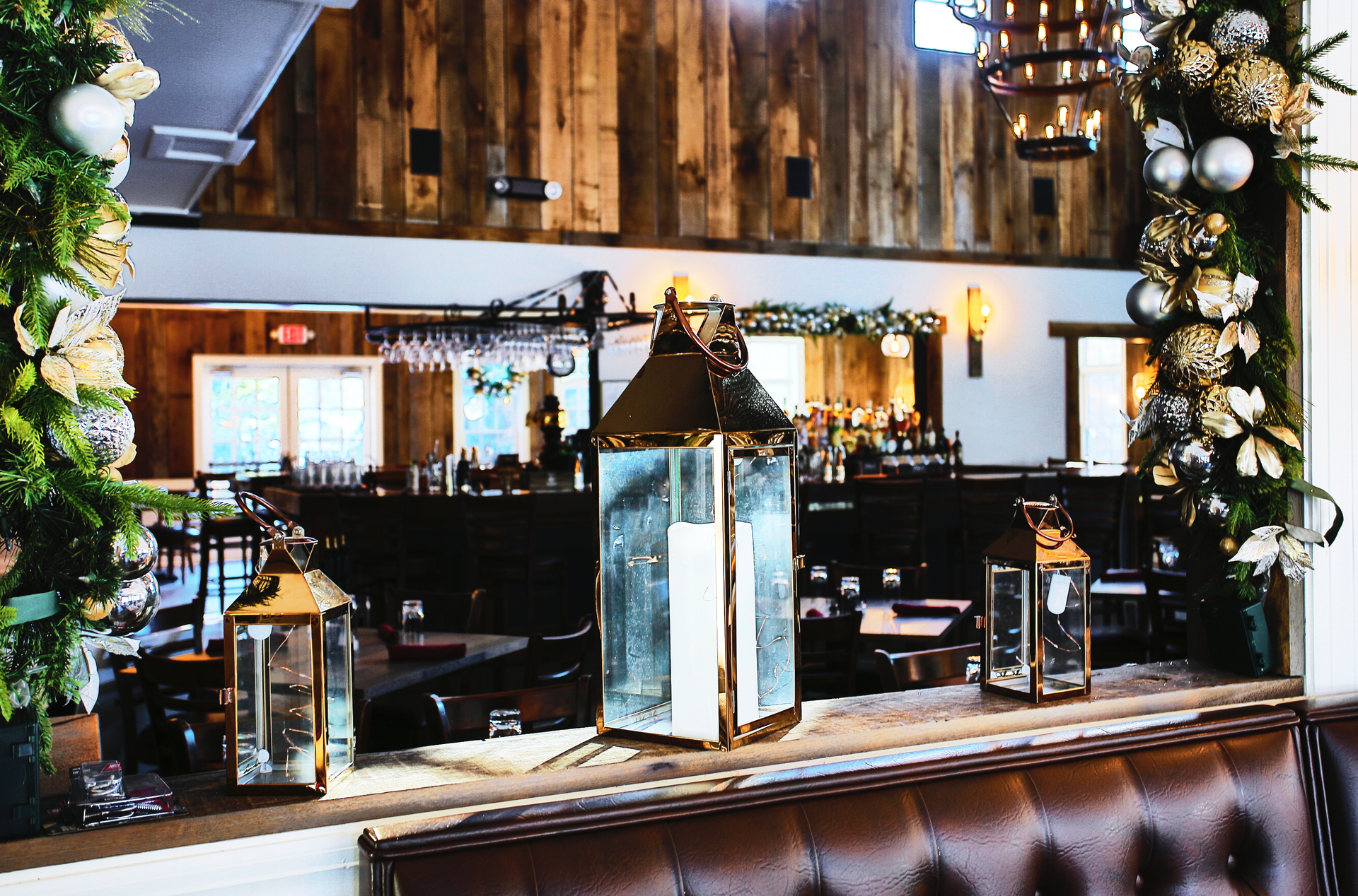 Restaurant interior with lanterns on a ledge, bar in the background, and holiday decorations.