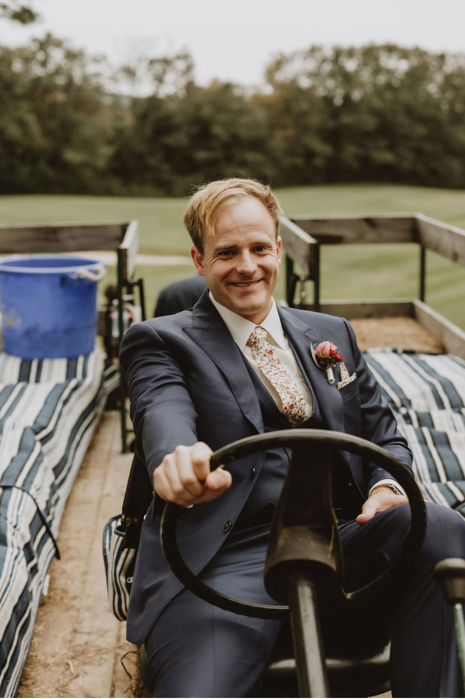 A man in a suit and tie is driving a tractor.