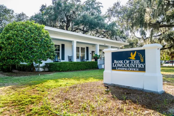 bank of the lowcountry's beaufort loan production office, a white building with a sign in front of it that with the name of the facility and logo