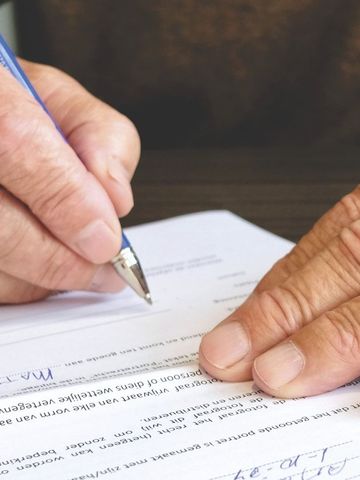 a person is writing on a piece of paper with a pen