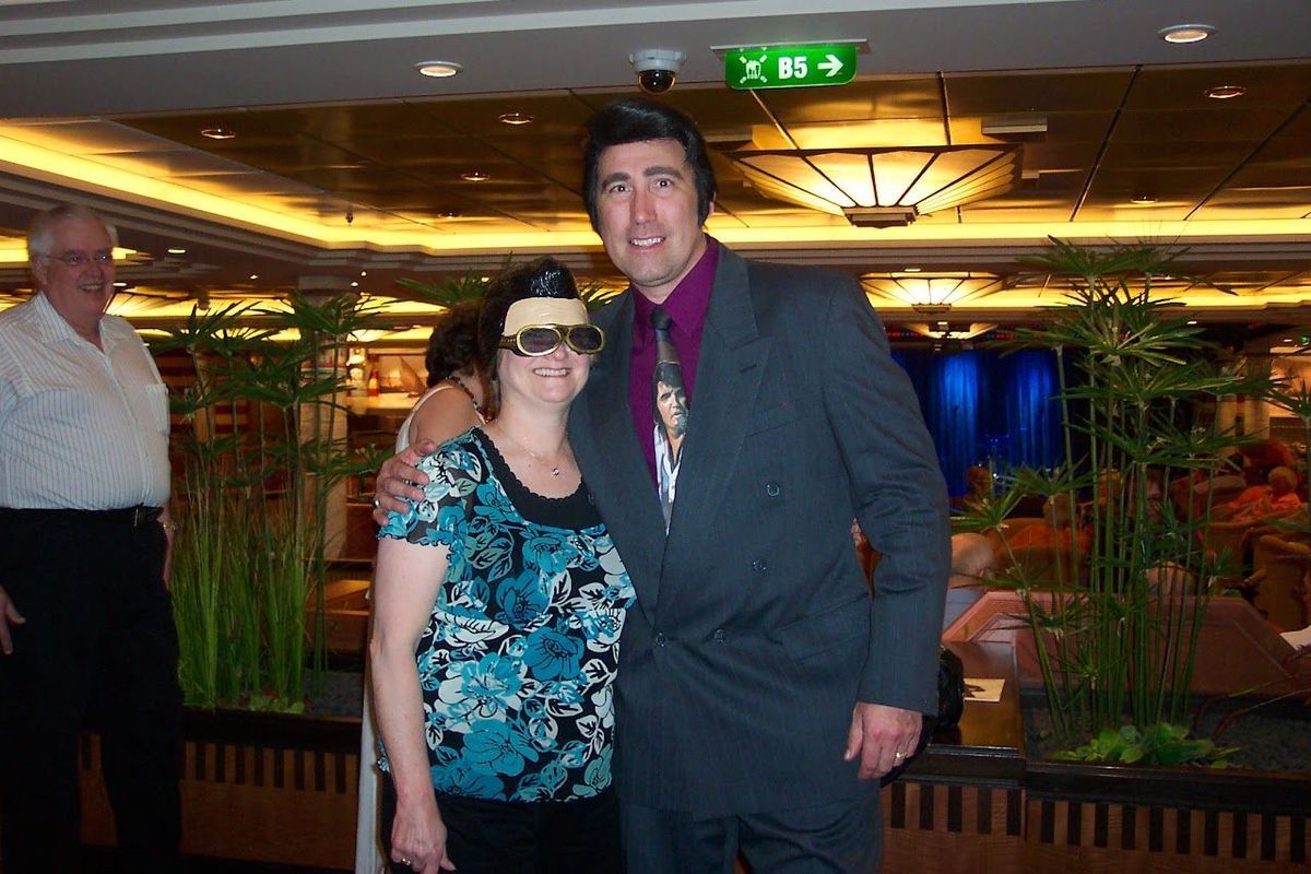 Two people posing together in a warmly lit indoor venue with plants and lounge seating