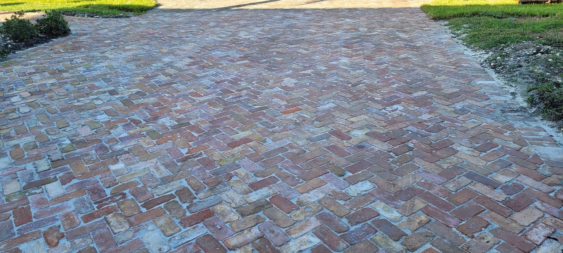 Brick-paved path with a herringbone pattern, bordered by grass