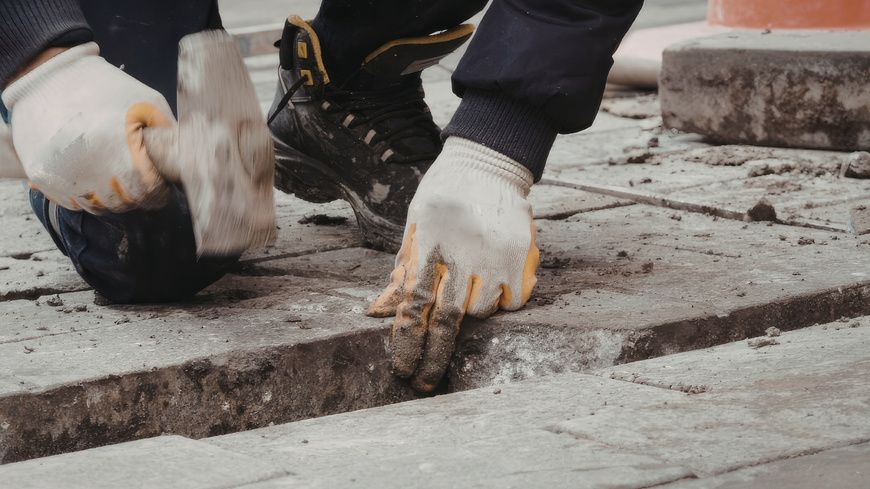Hand troweling mortar onto a surface between laid floor tiles.