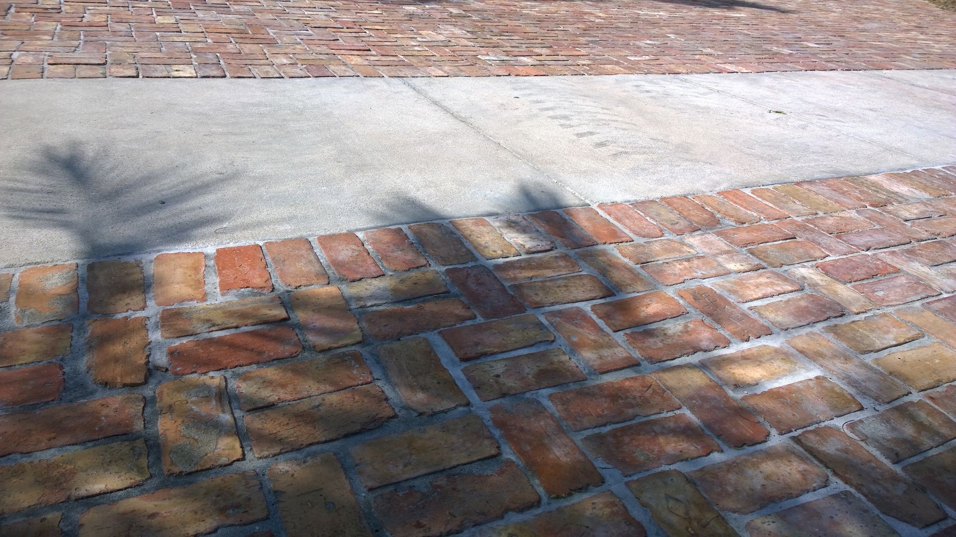 Brick pavement and wall with long tree shadows cast across the sunlit ground