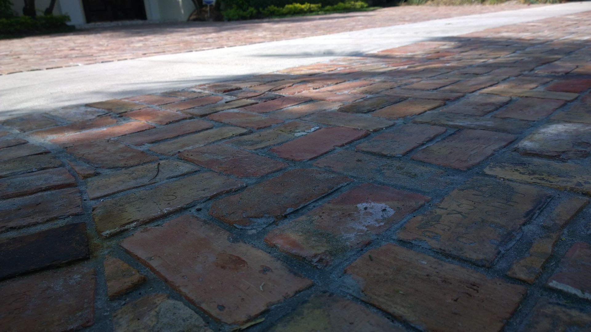 Brick-paved walkway with a low curb beside a road in daylight