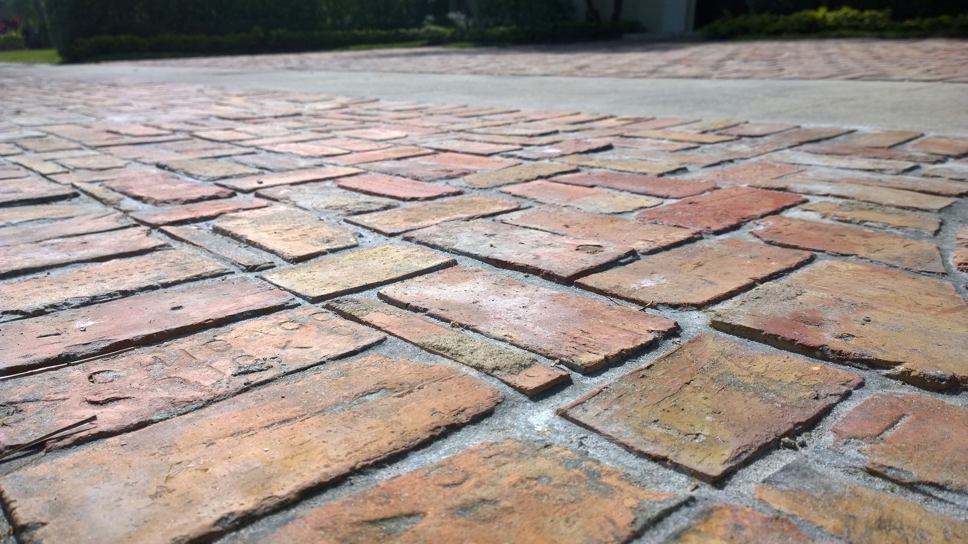 Close-up of weathered brick pavers in warm tones, laid in a patterned walkway.