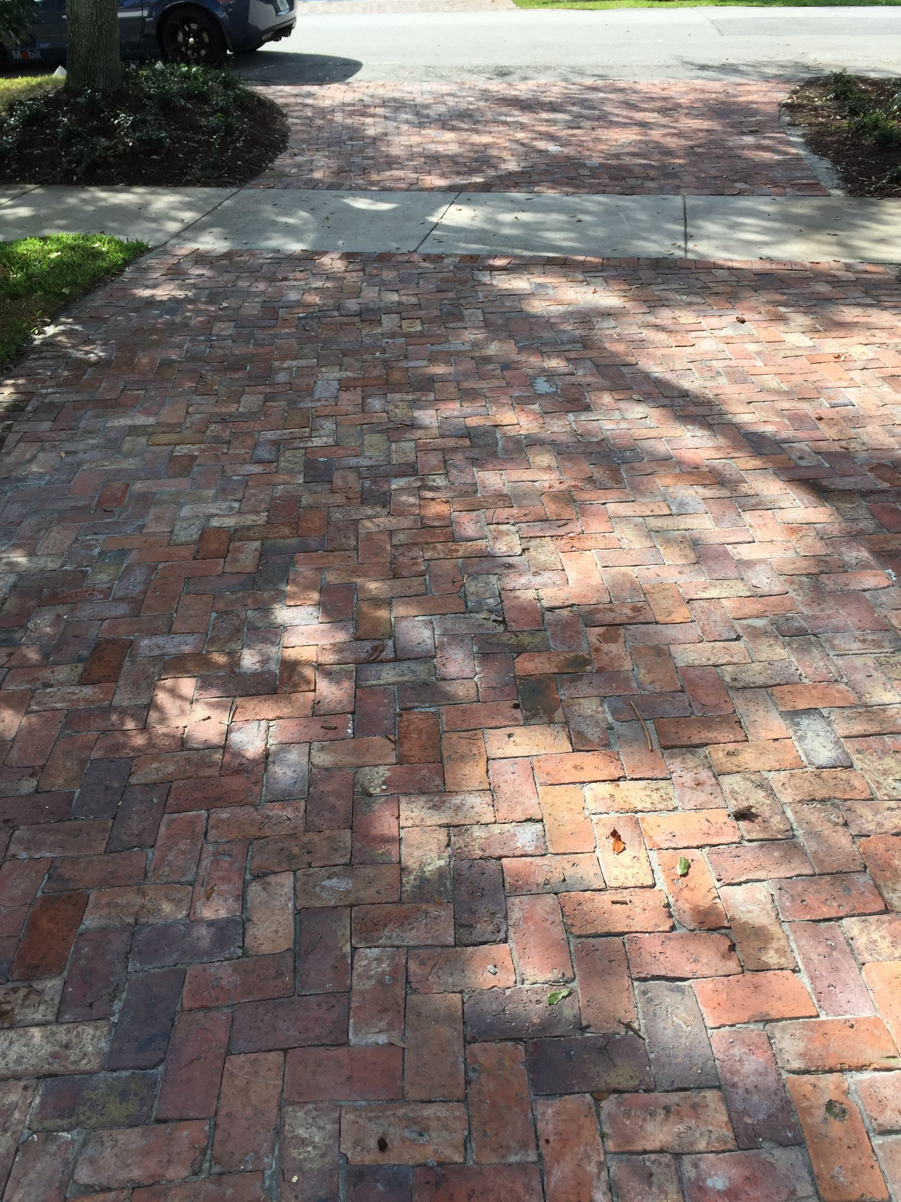 Roller applying black sealant to a white concrete surface.